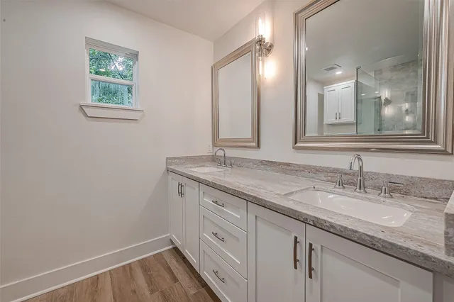 a bathroom with a granite countertop sink mirror and cabinets