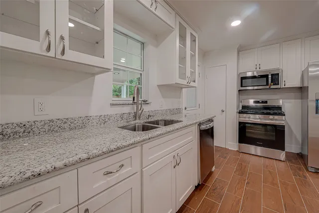 a kitchen with granite countertop a sink stainless steel appliances and cabinets