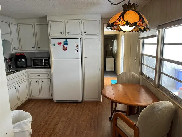 a kitchen with stainless steel appliances a stove a refrigerator and a dining table with wooden floor