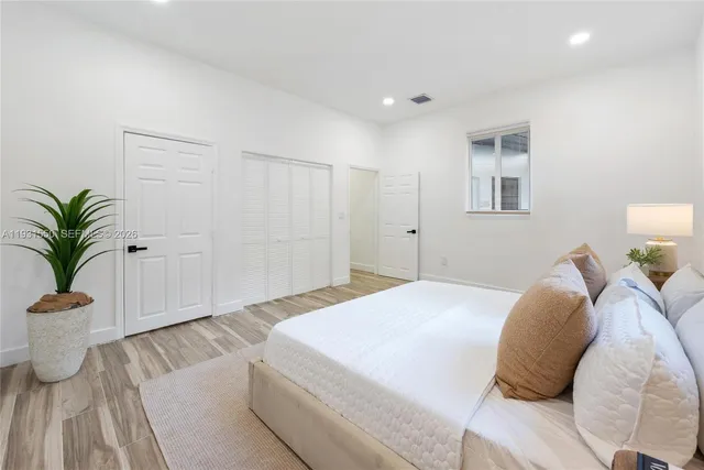 a spacious bedroom with a bed and a potted plant