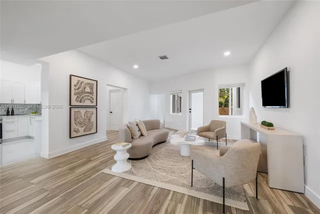 a living room with furniture a flat screen tv and wooden floor