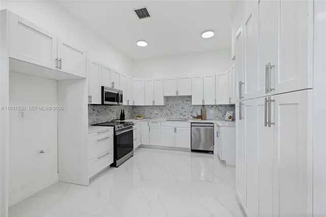 a kitchen with stainless steel appliances white cabinets and a refrigerator