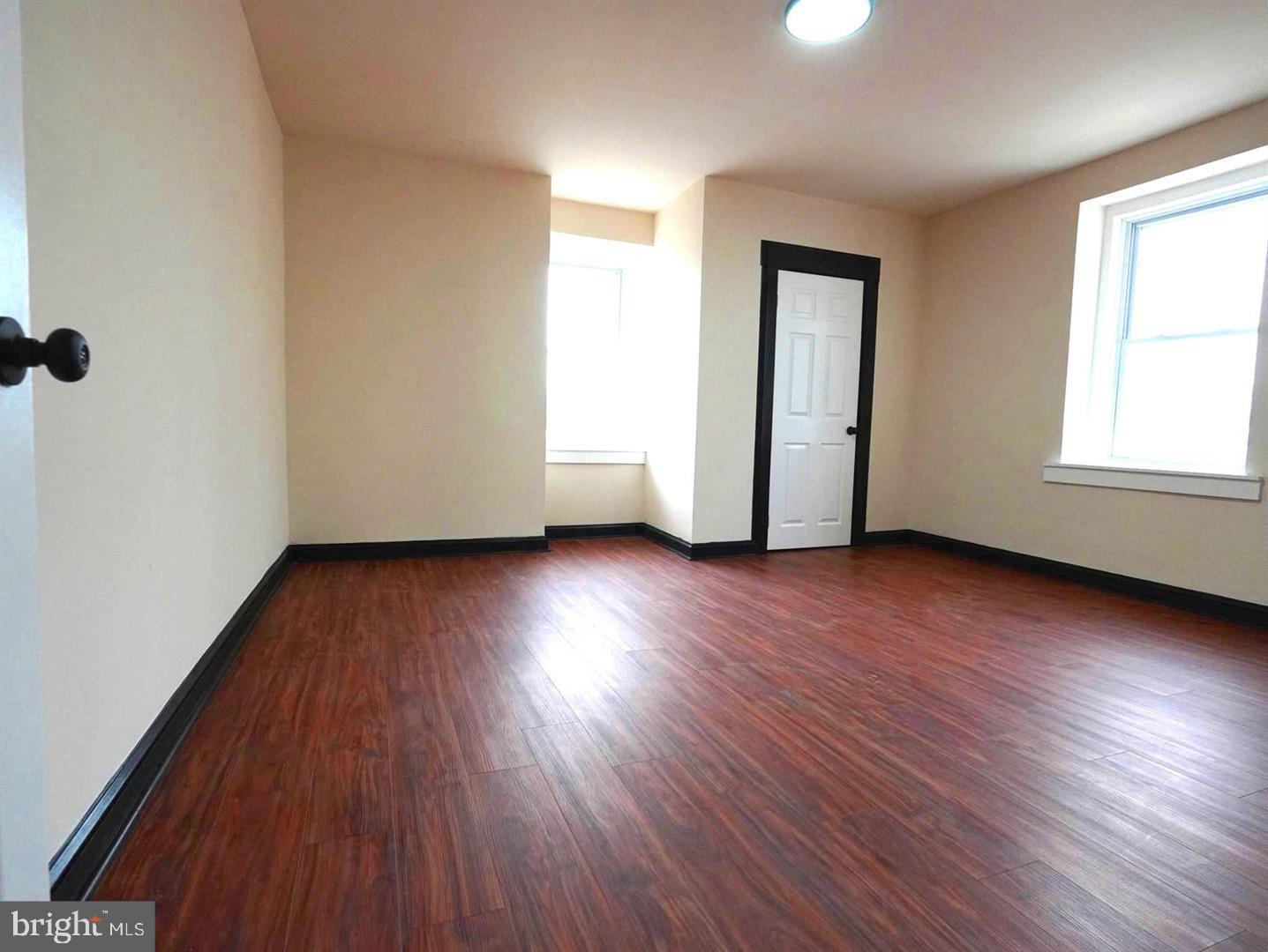 5013 Chester Avenue, Unit 1 Philadelphia, PA 19143 - Photo 10 of 12 an empty room with wooden floor and windows