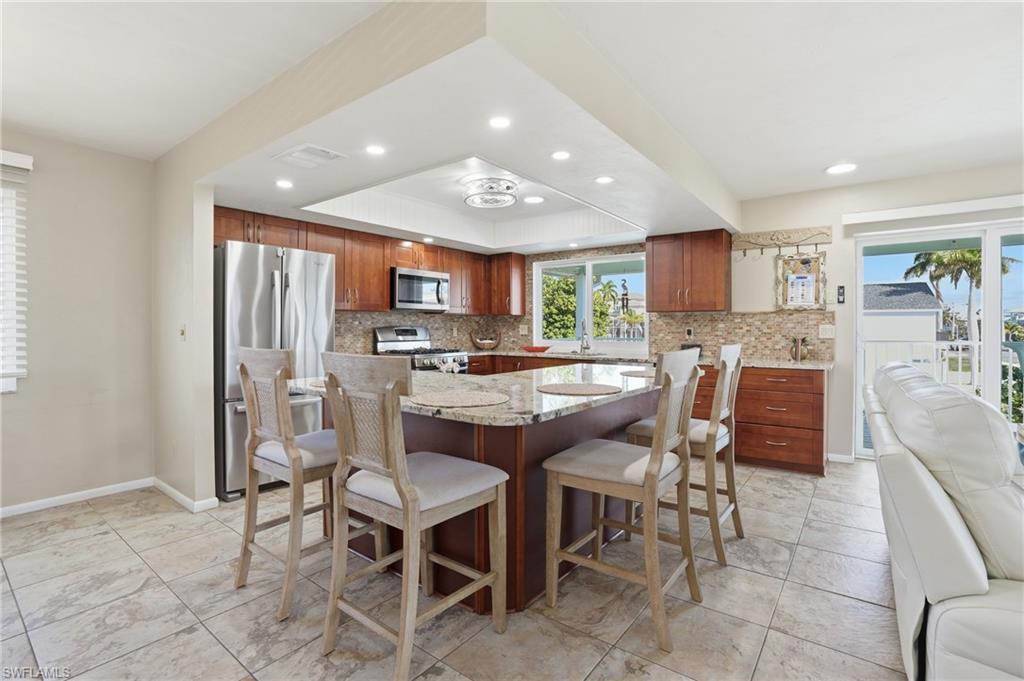 170 Redfish Road Fort Myers Beach, FL 33931 - Photo 14 of 48 a kitchen with stainless steel appliances kitchen island granite top and refrigerator