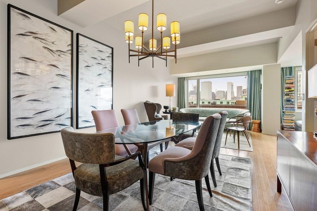 a dining room with wooden floor a chandelier a glass table and chairs