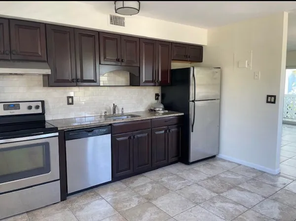 a kitchen with granite countertop wooden cabinets a refrigerator and a stove