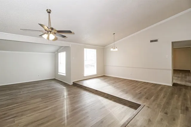 a view of empty room with wooden floor and ceiling fan