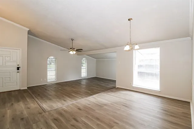 a view of an empty room with a window and wooden floor