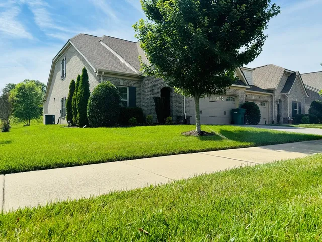 a front view of a house with a garden and trees