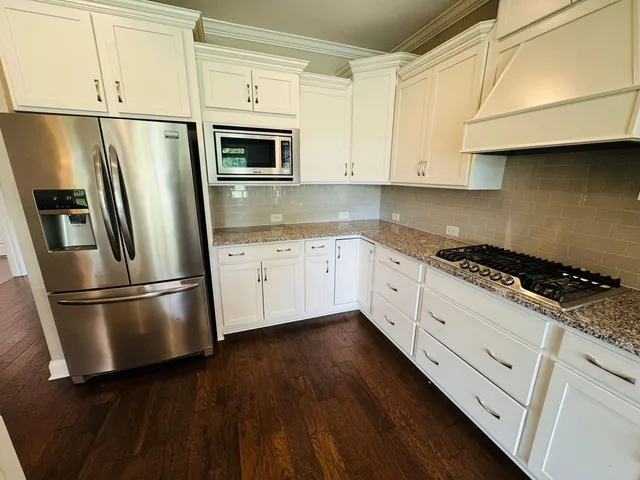 a kitchen with granite countertop white cabinets and stainless steel appliances
