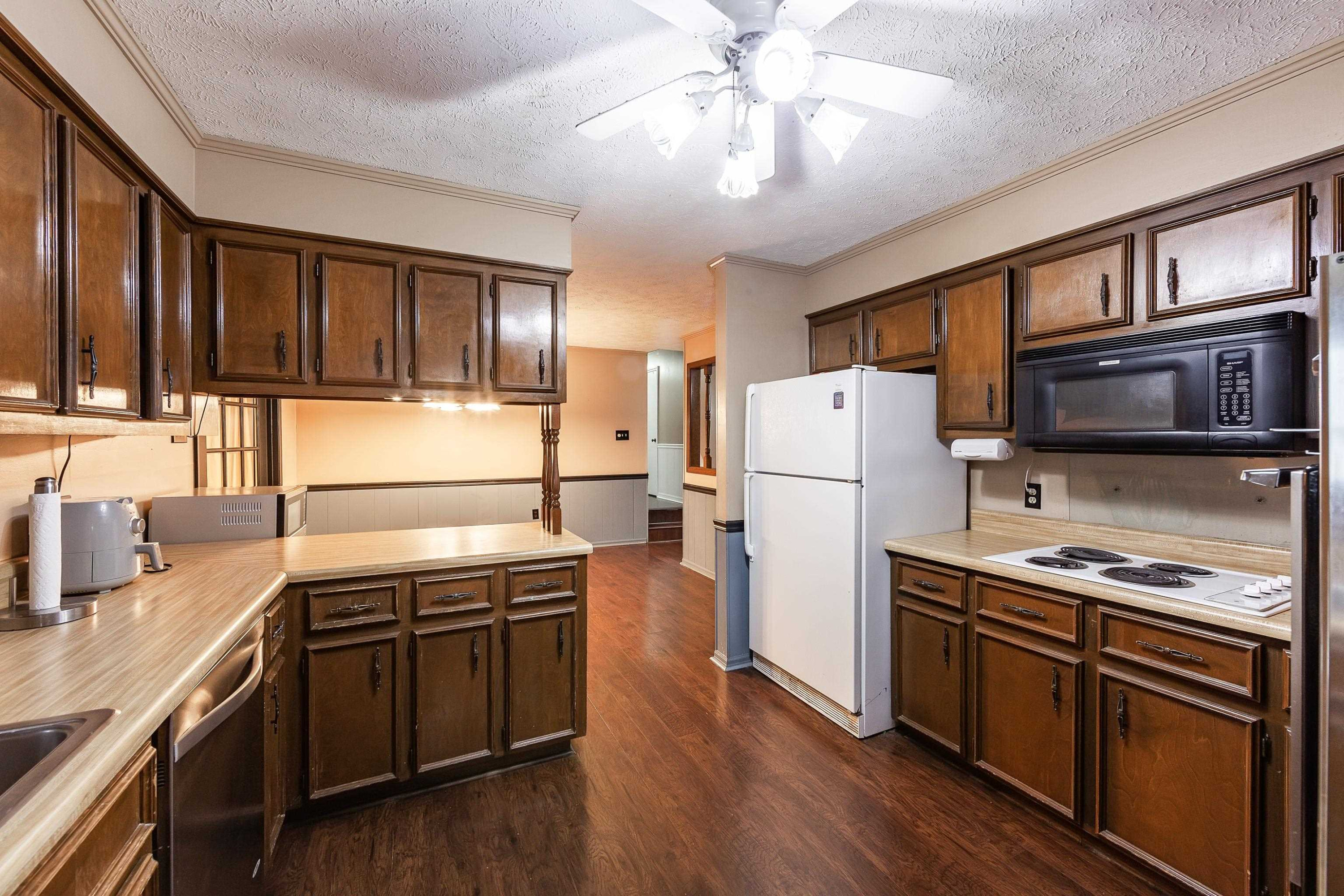 823 Potts Chapel Road Jackson, TN 38305 - Photo 3 of 24 a kitchen with stainless steel appliances granite countertop a stove top oven a refrigerator a sink and dishwasher with wooden floor