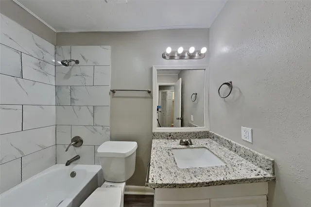 a bathroom with a granite countertop sink a toilet and shower