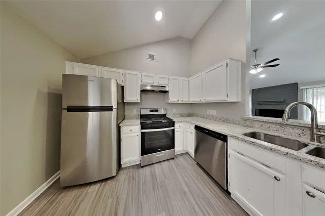 a kitchen with granite countertop a refrigerator stove and sink