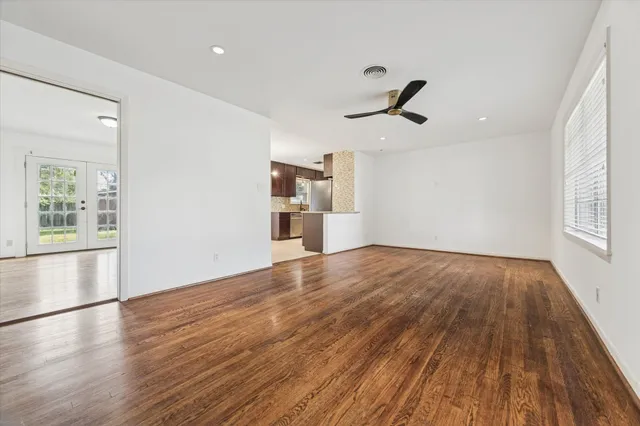an empty room with wooden floor and windows