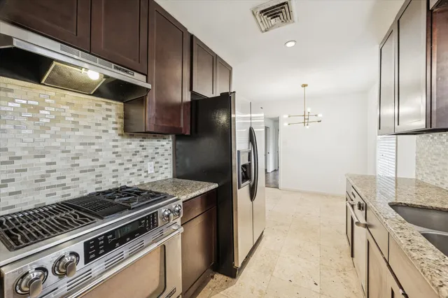 a kitchen with granite countertop a stove and a refrigerator