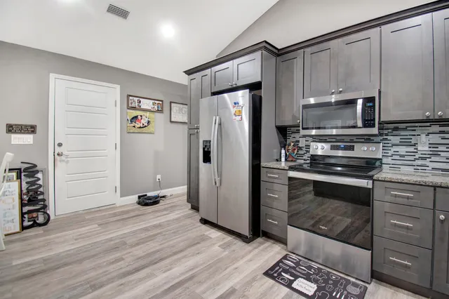 a kitchen with granite countertop a refrigerator stove and microwave