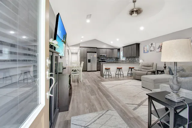 a living room with stainless steel appliances furniture a rug and a kitchen view