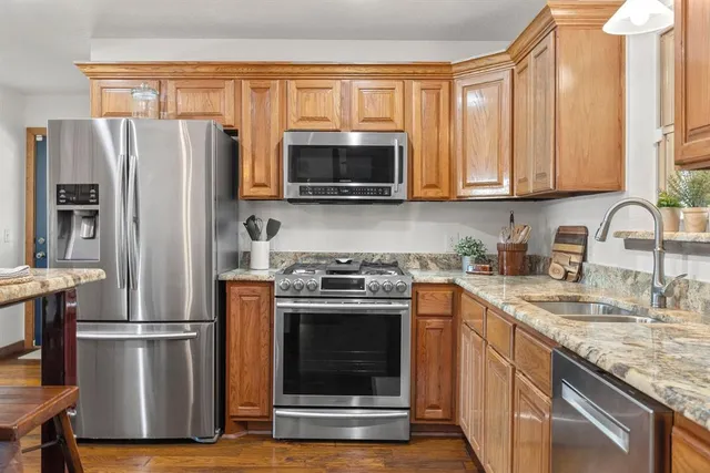 a kitchen with granite countertop a refrigerator stove and microwave