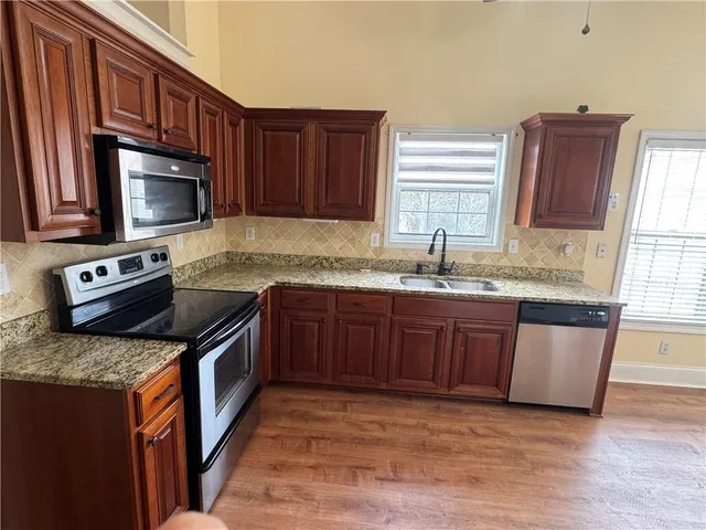 a kitchen with stainless steel appliances granite countertop a sink stove and microwave