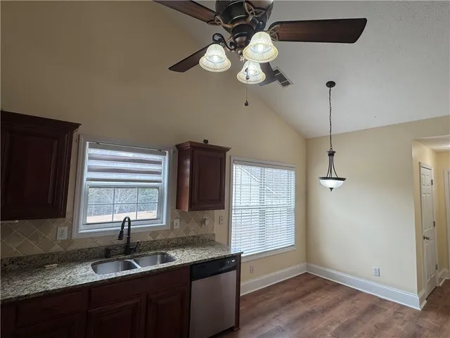 a kitchen with stainless steel appliances granite countertop a sink a window and cabinets