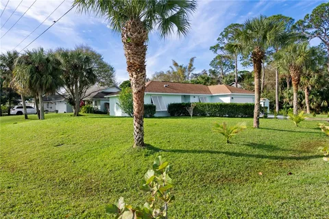 a view of a house with a big yard and palm trees