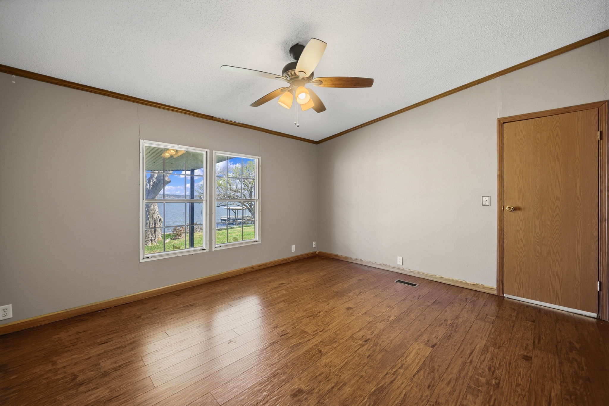 207 Vivian Road Onalaska, TX 77360 - Photo 27 of 33 an empty room with wooden floor chandelier fan and windows