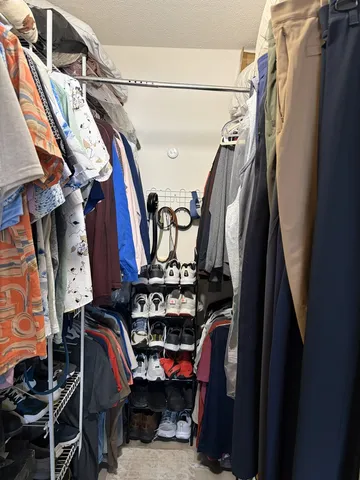 a view of walk in closet with clothes and shoes