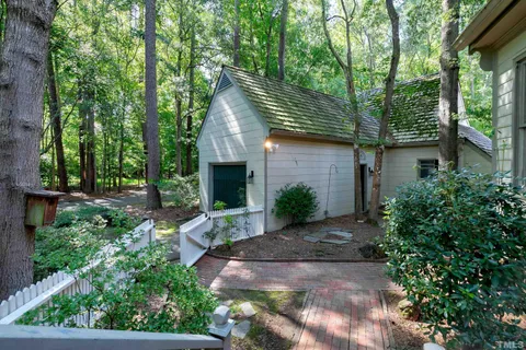 a backyard of a house with plants and large tree
