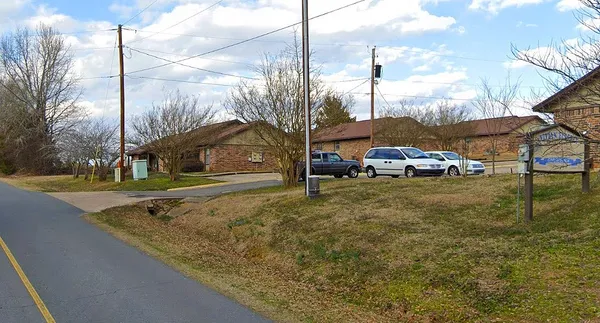 a yellow and view of a house with cars park