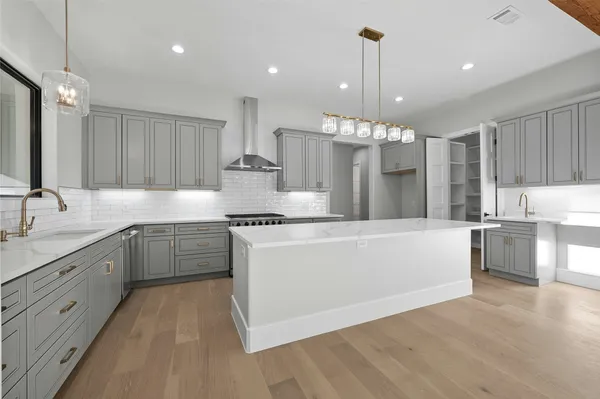a large kitchen with granite countertop a sink white cabinets and stainless steel appliances