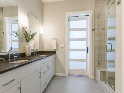 a spacious bathroom with a double vanity sink a mirror and a shower