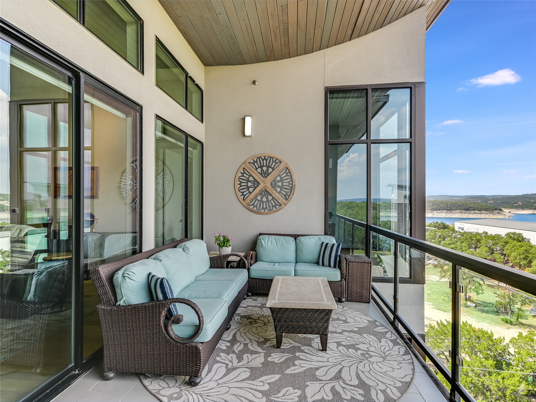 5921 Hiline Road, Unit 1501 Austin, TX 78734 - Photo 23 of 38 Sliding glass doors lead you outside to a spacious covered balcony highlighted by an upward-curving raised wood-planked ceiling and glass railing.