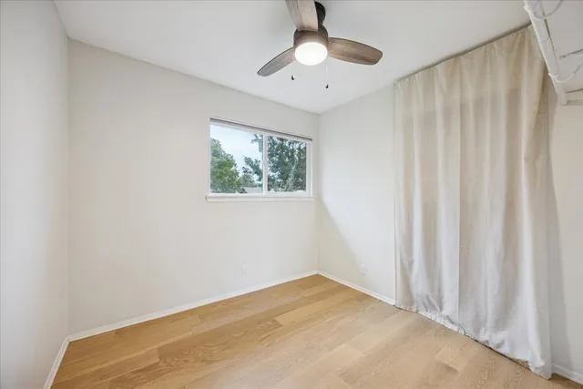 a view of empty room with window and ceiling fan