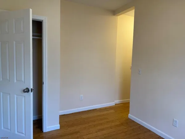 a view of an empty room with wooden floor and closet