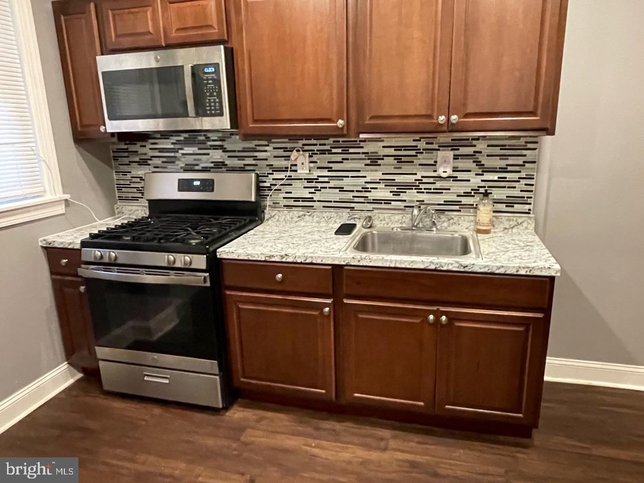 1115 West Wyoming Avenue Philadelphia, PA 19140 - Photo 10 of 33 a kitchen with granite countertop wooden cabinets and a stove top oven