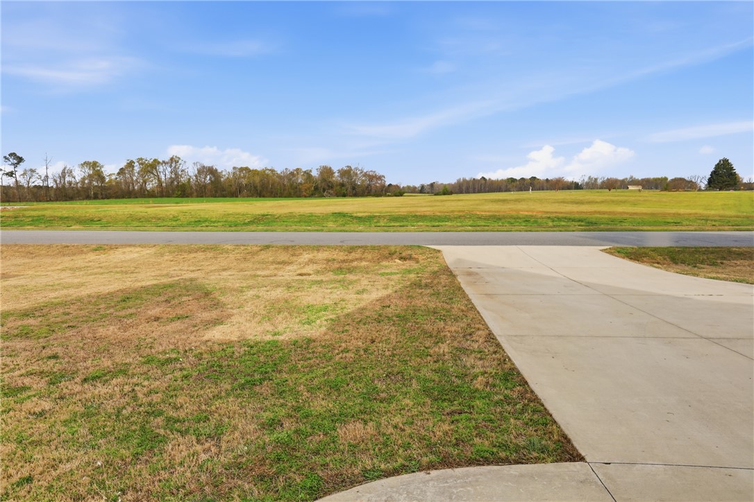 127 West Stewart Street Pelzer, SC 29669 - Photo 2 of 23 Expansive green fields unfold under a clear sky, offering a serene and open landscape.