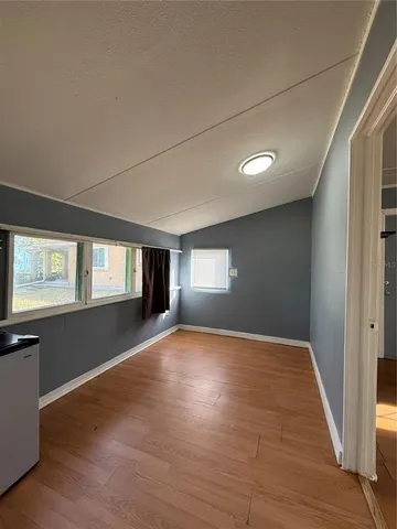 a view of an empty room with window and wooden floor
