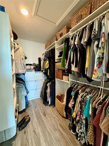 a view of walk in closet with clothes and shoes