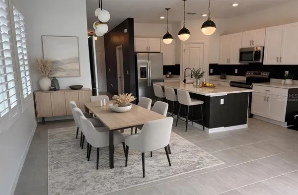 a kitchen with stainless steel appliances kitchen island granite countertop a sink a stove a refrigerator a microwave oven with white cabinets and wooden floor