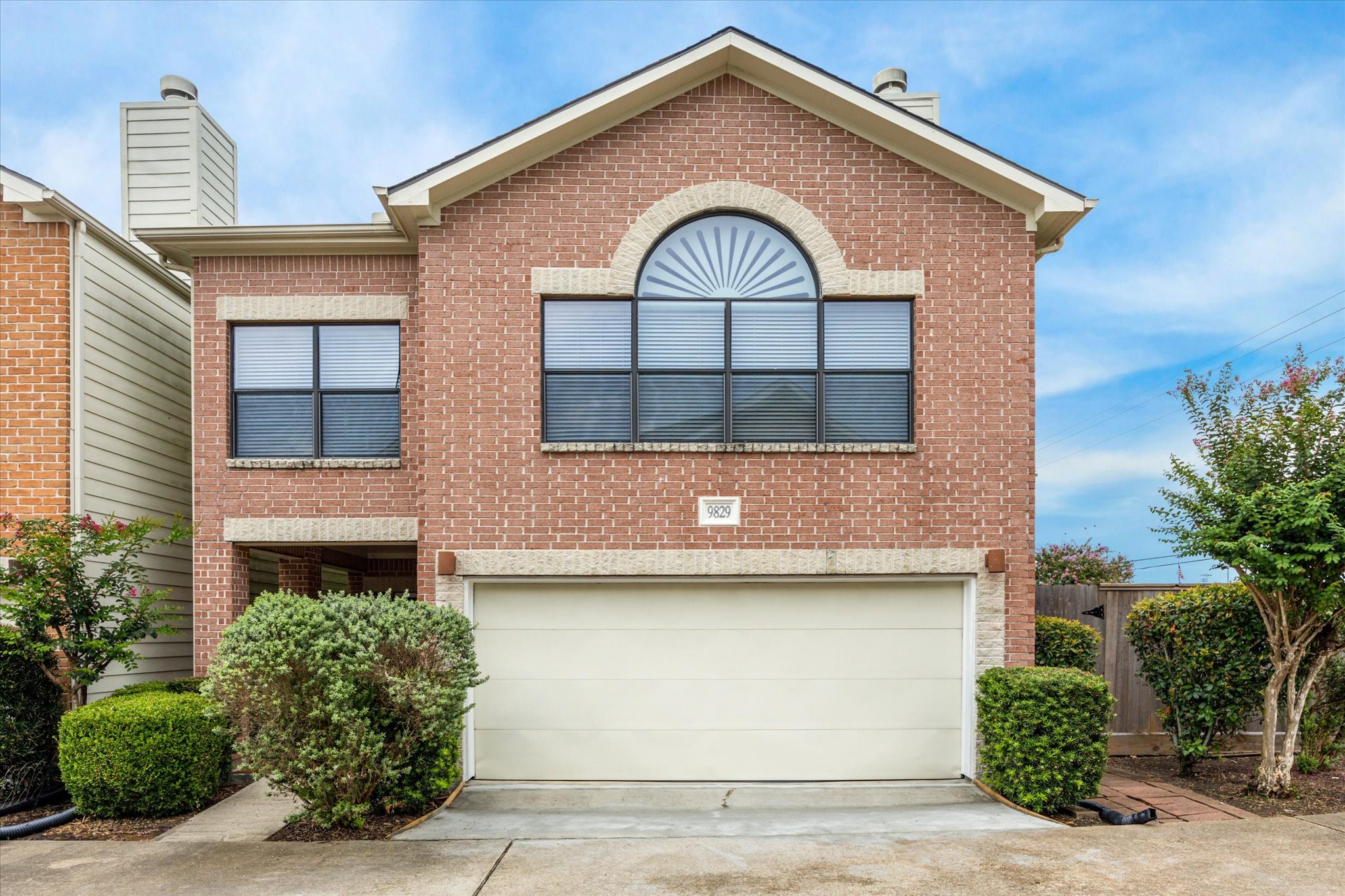 9829 Riddlelink Lane Houston, TX 77025 - Photo 1 of 22 Inviting brick facade with arched window detail, mature landscaping, and a private two-car garage in a quiet gated community.