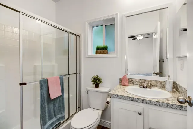 a bathroom with a granite countertop sink mirror vanity and toilet