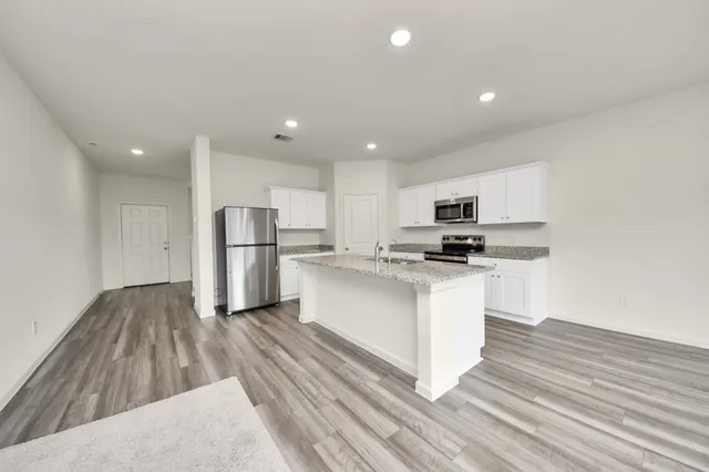 a kitchen with stainless steel appliances granite countertop a refrigerator sink and white cabinets