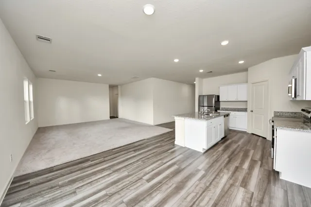 a large white kitchen with kitchen island a sink stainless steel appliances and cabinets