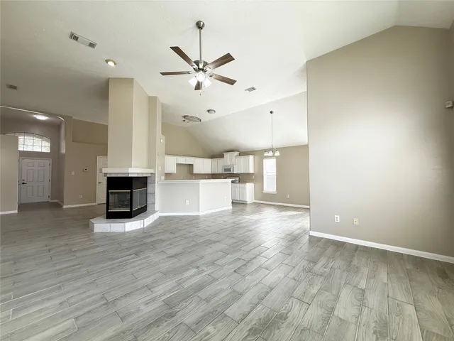 an empty room with wooden floor fireplace and windows
