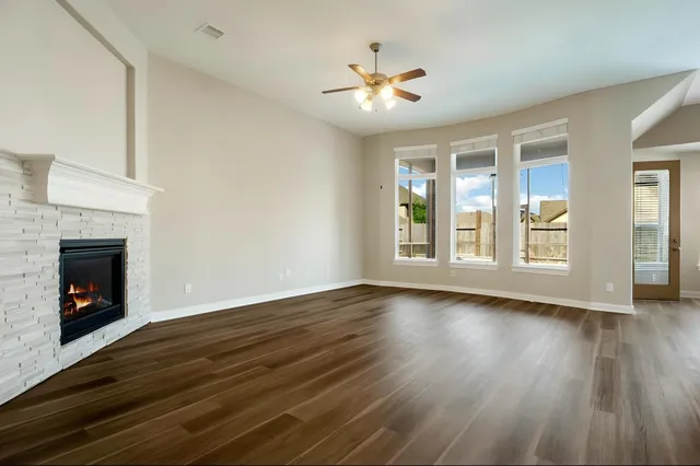 a view of an empty room with wooden floor fireplace and a window
