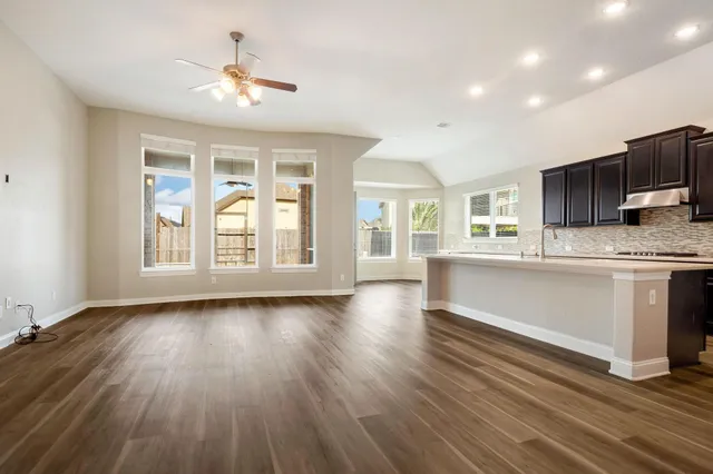 a kitchen with stainless steel appliances granite countertop a stove top oven a sink dishwasher a dining table and chairs with wooden floor