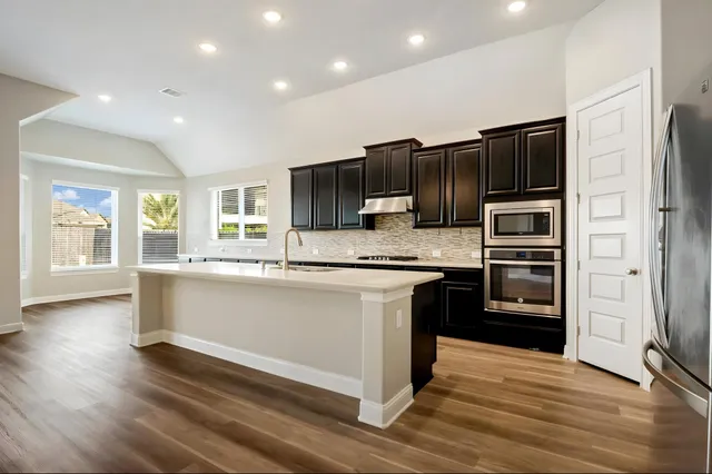 a large kitchen with stainless steel appliances granite countertop a stove a sink and a refrigerator