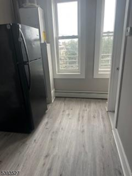 104 President Street, Unit 8 Passaic, NJ 07055 - Photo 4 of 8 a view of empty room with wooden floor and fan