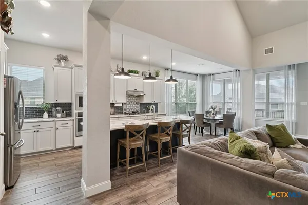 a kitchen with stainless steel appliances kitchen island granite countertop a refrigerator a sink a stove and white cabinets