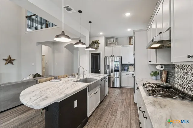 a large kitchen with stainless steel appliances granite countertop a lot of counter space and wooden floor